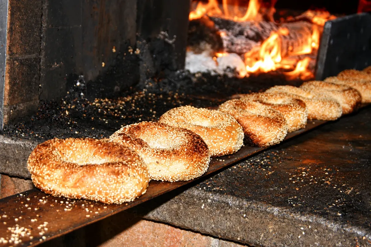 Bagels de sésamo en la pala de madera junto al horno.